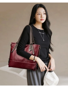 Detailed view of burgundy tote bag with brown straps and white contrast stitching