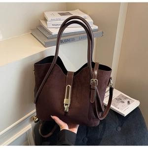 Detail of dark brown suede bucket bag featuring a golden twist-lock closure and slim handle