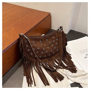 Détail d'un sac besace en daim marron foncé avec œillets argentés et franges de style bohème