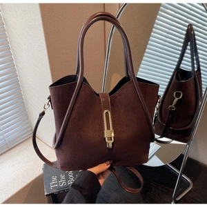 Detail of dark brown suede bucket bag featuring golden metal clasp and retro texture