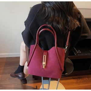 Close-up of wine red suede handbag with sleek leather handles and gold metal buckle
