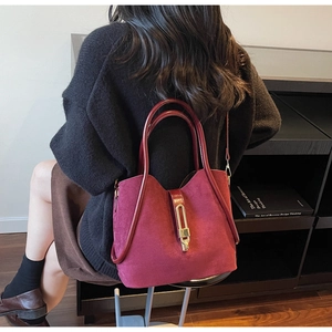 Burgundy faux suede bucket bag with gold lock shown in a lifestyle street style setting