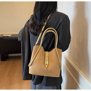Close-up of khaki suede bucket bag with gold clasp and elegant rolled top handle