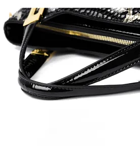 Detail of crocodile pattern faux leather handbag with gold zipper and sturdy handles
