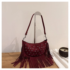 Gros plan d'un sac selle en daim bordeaux avec de longues franges et des œillets