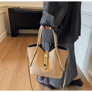 Detail of khaki suede bucket bag with metal lock buckle and adjustable shoulder strap
