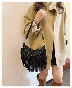 Sacoche noire à franges et clous argentés portée par un mannequin pour un look mode