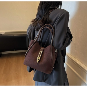 Detail of dark brown matte suede bucket bag with gold metal buckle on a model