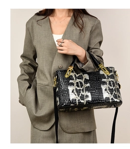 Detail of snake skin pattern faux leather handbag with golden lock and black shoulder strap