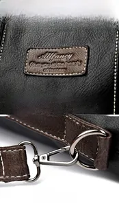 Detail of Allfancy logo embossed on textured leather and premium metal lobster clasp