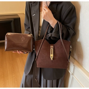 Close-up of retro brown suede tote with gold lock and matching leather pouch