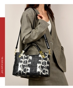 Macro detail of faux crocodile texture and gold hardware on black and white handbag