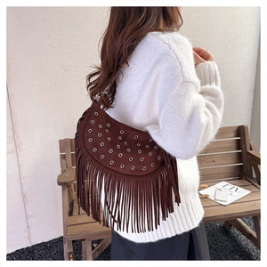 Gros plan du sac besace en daim marron avec franges et œillets métalliques cloutés