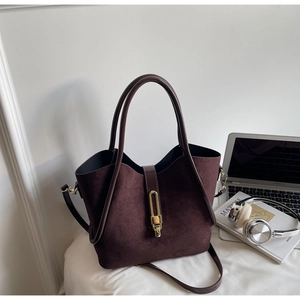 Detail of dark brown matte tote bag featuring a gold oval lock and textured suede finish