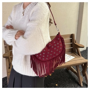 Détail du sac besace en daim bordeaux avec œillets argentés et franges bohèmes