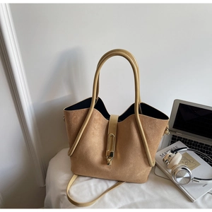 Detail of tan suede tote bag with smooth leather handles and metal clasp closure