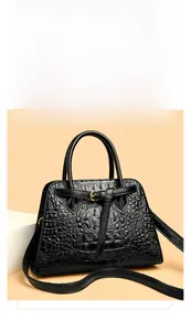 Detail of black crocodile texture tote bag with golden metal buckle and top handles