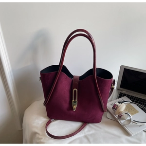 Close-up of matte burgundy bucket bag with golden buckle and sleek leather texture
