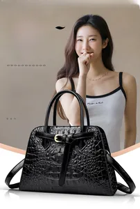 Detail of black crocodile texture handbag with gold hardware and trapezoid shape