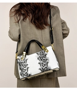 Detail of vintage white snakeskin pattern handbag with gold hardware on a gray suit model