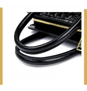 Detail of rounded double handles and gold zipper on black crocodile leather bag