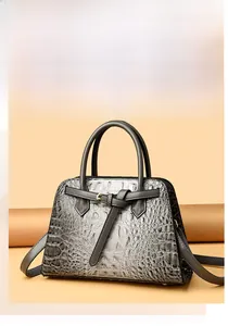 Close-up of gold metal buckle and stitching detail on grey crocodile pattern handbag