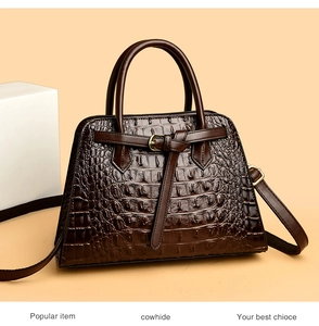Detail of dark brown crocodile embossed cowhide tote bag with sturdy handles and hardware