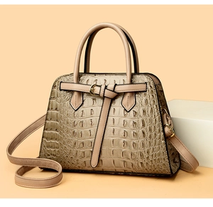 Macro detail of crocodile pattern leather on beige tote bag with golden hardware