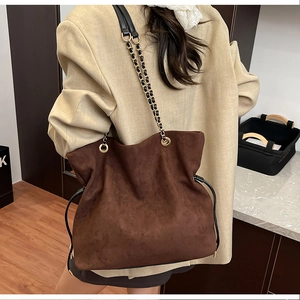Close-up of retro brown faux suede bucket bag with chain strap and drawstring detail