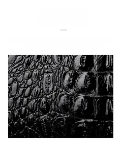 Close-up of black crocodile embossed faux leather with a glossy oil wax finish texture
