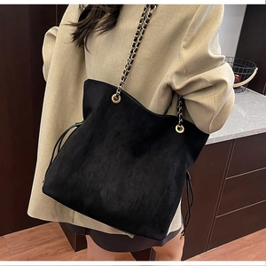 Detail of black suede bucket bag with metal chain strap and drawstring closure