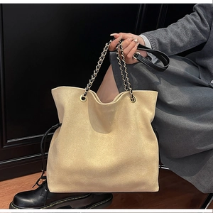 Detail of apricot suede bucket bag with gold chain strap and drawstring closure