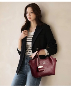 Detail of wine red quilted bucket bag with kangaroo logo and matching charm on model