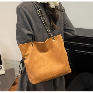 Detail of vintage brown suede bucket bag with gold chain strap and drawstring accents