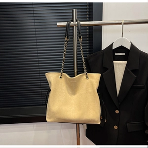 Detail of beige suede drawstring bucket bag with black chain strap on professional display