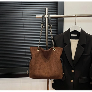 Detail of vintage dark brown suede bucket bag with drawstring and metal chain strap