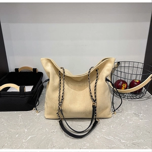 Close-up of beige hobo bucket bag with leather and metal chain woven shoulder strap