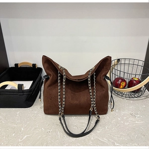 Detail of dark brown suede bucket bag with side drawstring and metal chain strap