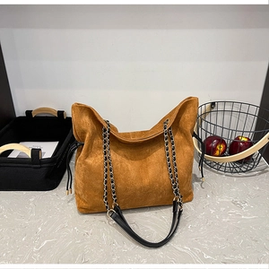 Detail of deep brown suede bucket bag featuring drawstring closure and black gold chain strap