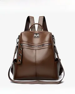 Dettaglio di uno zaino in pelle marrone con trama litchi, zip argentate e decorazioni in metallo