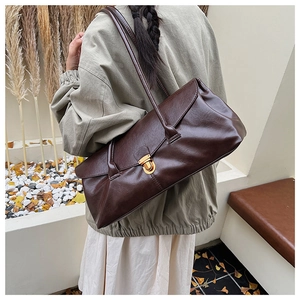 Detail of vintage dark brown baguette bag with glossy texture and gold metal buckle
