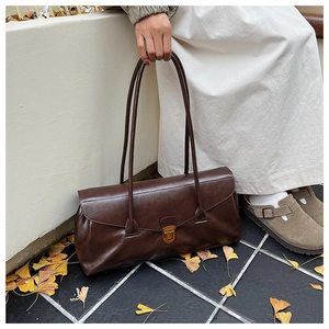 Detail of a dark brown vintage shoulder bag with bronze buckle and polished leather texture