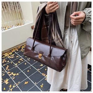 Close-up of brown retro baguette bag featuring a golden buckle and double shoulder straps