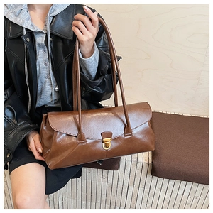 Detailed macro view of the vintage brown leather bag with a classic bronze metallic buckle