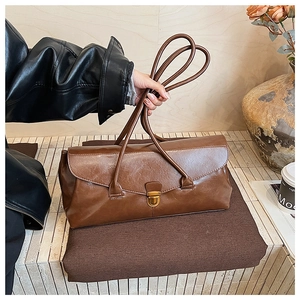 Detail of vintage brown baguette bag featuring double handles and a gold metal buckle
