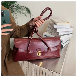 Detail of vintage burgundy shoulder bag featuring a classic gold metal buckle closure