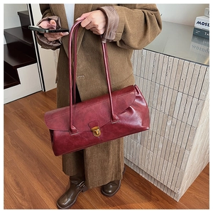 Detail of vintage dark red matte leather shoulder bag with gold clasp shown by model