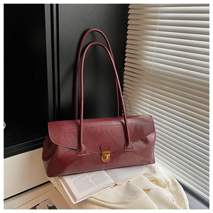 Close-up of burgundy rectangular shoulder bag with golden buckle on books