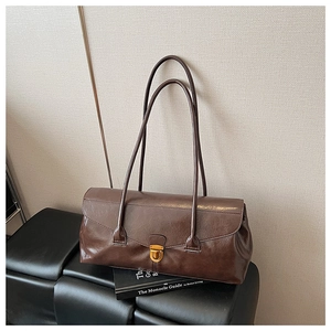 Close-up of vintage brown shoulder bag with a polished golden oval lock on textured bench