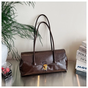 Detailed close-up of dark brown leather baguette bag with a vintage gold clasp